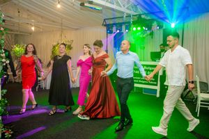 Wedding party dancing in a venue with dramatic green and blue lighting effects.