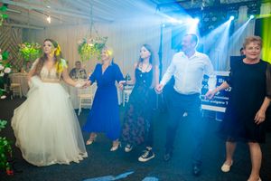 Wedding celebration in a tent venue with blue spotlights and guests dancing.
