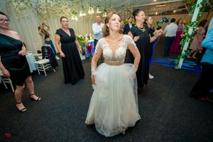 Wedding celebration in full swing with guests dancing under decorative lighting and floral arrangements.