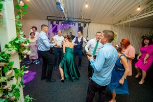 Wedding guests dancing and mingling on the dance floor under colorful party lights.