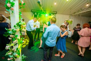 Wedding venue decorated with green balloon arrangements and string lights during evening celebration.