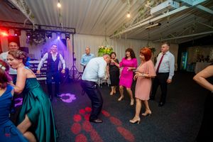 Wedding reception dance floor illuminated with purple and blue lighting as guests celebrate.