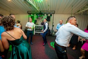 Guests enjoying a lively dance party with green ambient lighting at a wedding reception.