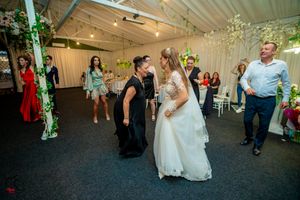 Wedding reception dance floor with colorful lighting and guests dancing in a decorated indoor venue.