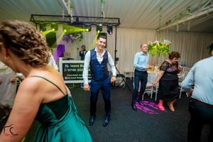 Wedding celebration with green lighting and floral decorations on the ceiling.