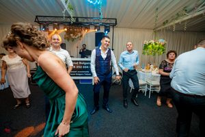 Wedding party dancing and celebrating under blue and green ambient lighting.