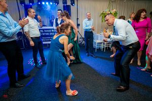 Energetic dancing scene at a wedding reception under dramatic blue lighting.