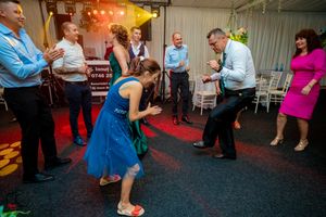 Wedding celebration with guests dancing under red and yellow spotlights in a decorated venue.