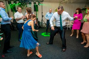 Guests dancing and interacting on a dark dance floor with green lighting effects.