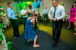 Guests enjoying a lively dance moment at a wedding reception with green ambient lighting.