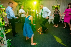 Wedding party dancing under vibrant green and yellow lights on a dark dance floor.