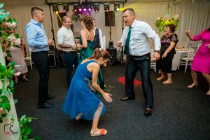 Guests dancing energetically at a wedding reception with colorful lighting and floral decorations.