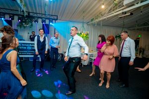 Reception hall with blue lighting and guests dancing during an evening celebration.