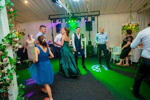Event space with green lighting effects and guests enjoying a lively dance floor atmosphere.