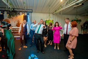 Reception venue with guests dancing and mingling under colorful mood lighting.