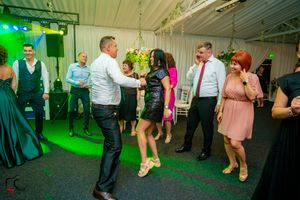 Party guests dancing and socializing under vibrant green lighting at an indoor celebration.
