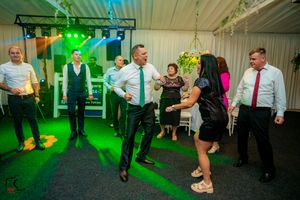 Reception venue with green lighting and guests enjoying the dance floor.