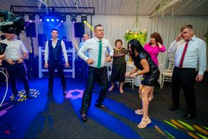 Wedding celebration with blue lighting and guests dancing in a decorated indoor space.