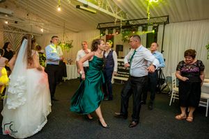 Wedding party dancing in a decorated indoor venue with dramatic lighting effects.