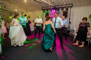 Wedding celebration in a tent venue with colorful lighting and guests dancing.