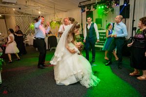 Wedding reception dance floor illuminated with green lighting as guests dance and celebrate.
