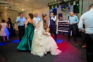 Wedding reception dance floor filled with guests in formal attire and colorful lighting.
