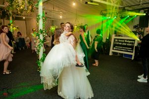 Wedding venue decorated with green lighting and natural foliage elements.
