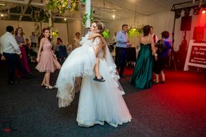 Wedding reception venue with colorful lighting and guests mingling in formal attire.