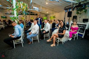 Wedding reception venue with rows of chairs and guests under green accent lighting.