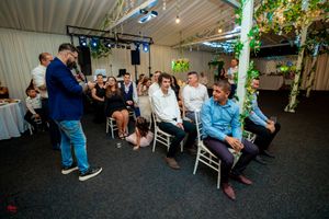 Wide shot of a wedding reception venue with guests seated at tables and decorative lighting.