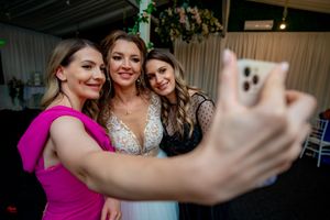 Wedding guests taking selfies and celebrating together at an indoor reception.