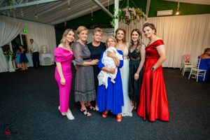 Wedding guests in colorful dresses enjoying themselves on the dance floor at a reception.