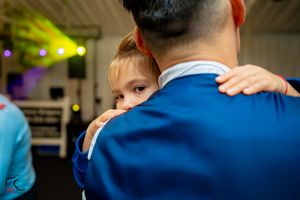 Close-up shot of a tender moment during a wedding dance with a navy blue suit.