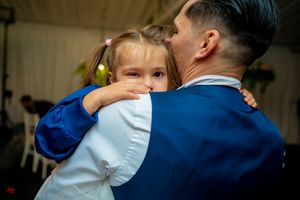 An emotional embrace during a wedding dance with a bright blue suit visible.