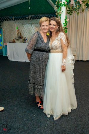 Guests pose together at a wedding reception with decorative curtains and greenery in the background.
