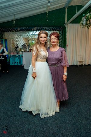 Wedding guests in formal attire dancing on a dark floor under decorative lighting.