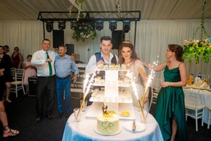 Wedding reception venue with elegant table settings and decorative lighting under a white tent ceiling.