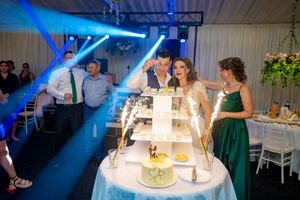 Wedding reception space with dramatic blue lighting and elegant cake display centerpiece.