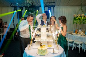 Wedding venue with theatrical lighting effects highlighting the dance floor and cake display.
