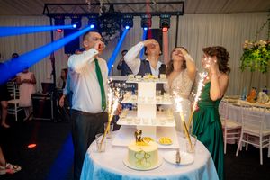 Wedding reception celebration with dramatic blue lighting and multi-tiered cake display.