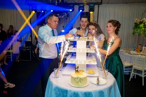 Reception hall with blue lighting effects highlighting wedding celebration and cake display.