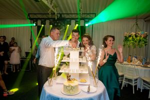 Wedding venue decorated with emerald green lighting and white table settings.