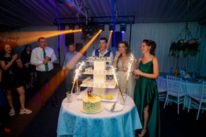 Wedding celebration venue with multicolored lighting effects and centerpiece cake display.
