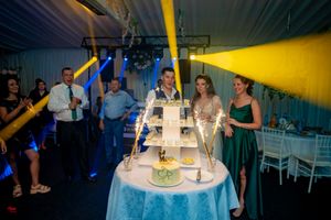 Wedding venue with warm yellow lighting highlighting the cake display and guest tables.