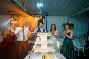 Wedding reception moment captured with warm lighting around tiered cake display and sparklers.
