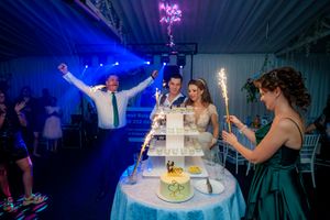 Energetic celebration around a wedding cake tower with sparklers and dramatic blue lighting effects.