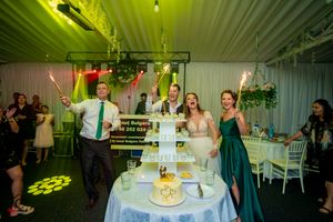 Wedding reception with green lighting effects and sparklers around multi-tiered display on table.