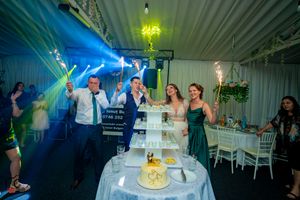Energetic wedding celebration with blue lighting effects and sparklers around tiered display.