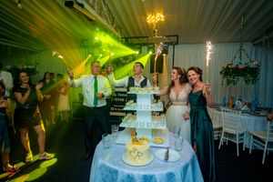 Wedding celebration with green lighting effects and sparklers surrounding an elegant tiered display.