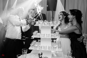 Black and white photo of wedding cake cutting moment with sparklers adding celebratory flair.
